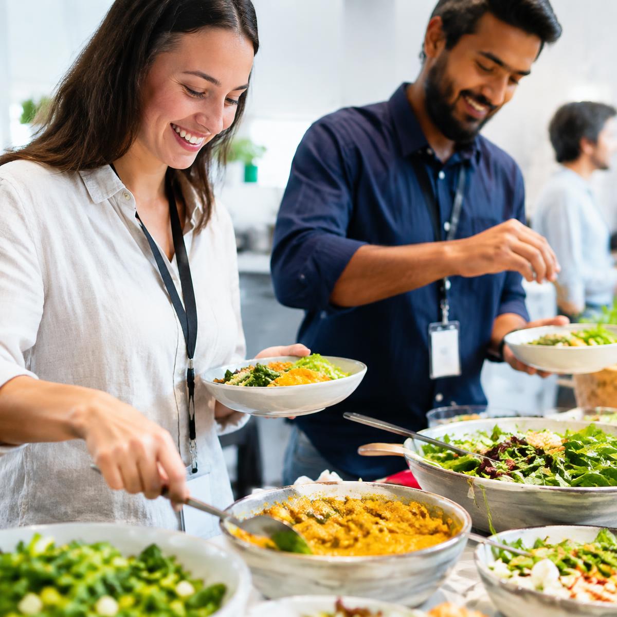 Kolleg:innen bedienen sich lächelnd am frischen Buffet